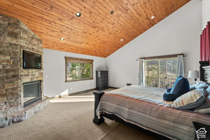 Vaulted wood-paneled ceiling, stone-clad fireplace, built-in television, and an outdoor balcony