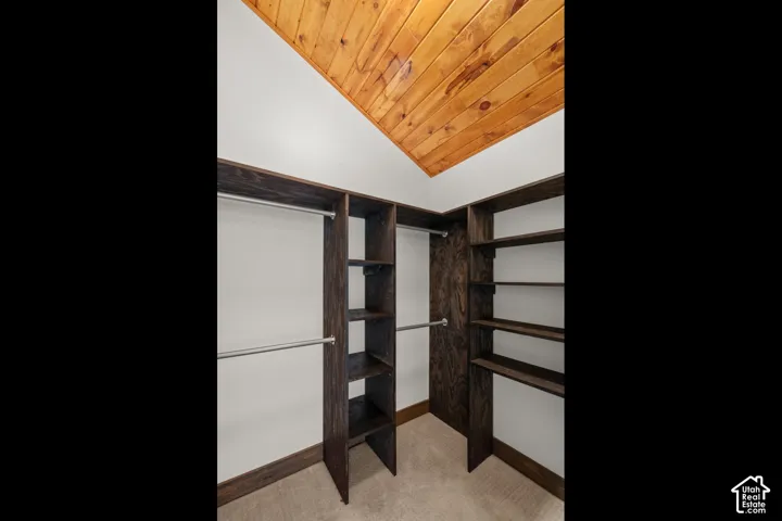Built-in dark wood-finish shelving and hanging rods with a sloped wood-paneled ceiling