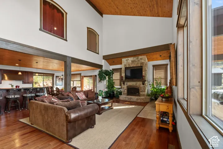 Vaulted ceiling with wood-finish planks, stone-clad fireplace, wood-finish flooring, and recessed lighting