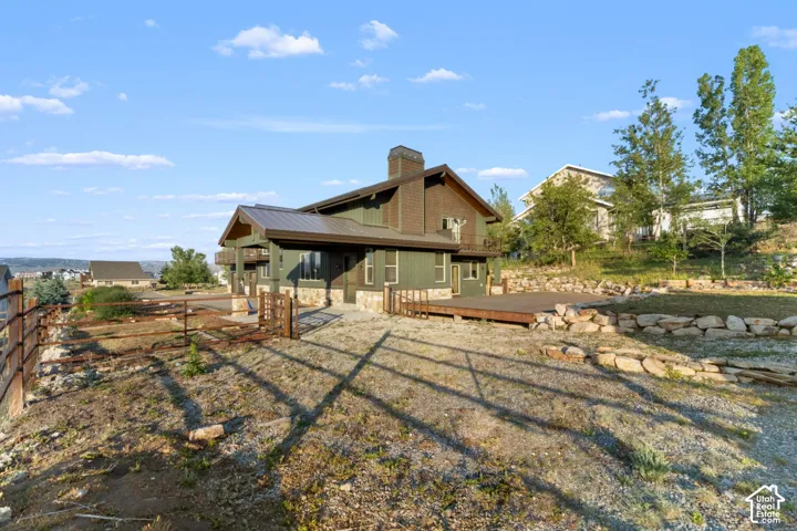 Two-story exterior with a metal roof, stone facade accents, and a wood deck