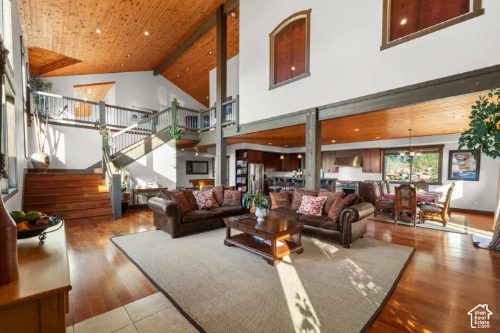 Vaulted ceilings with wood-paneled accents, hardwood flooring, an open-concept layout, and a prominent staircase with a landing