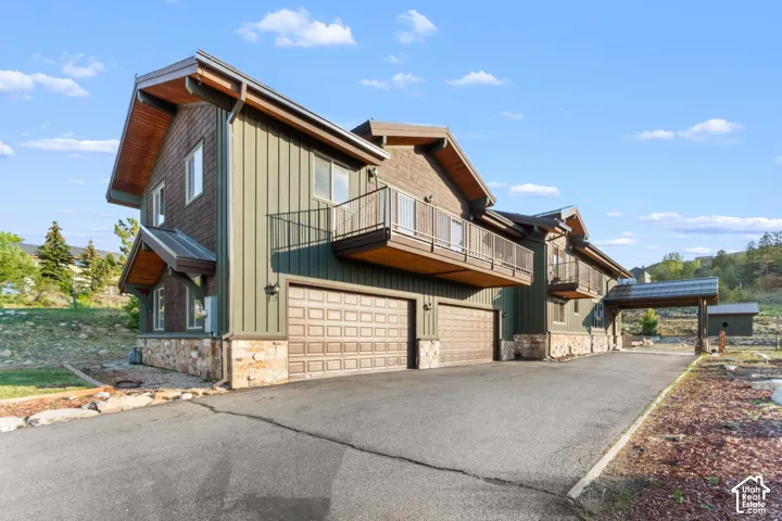 Modern architectural home featuring a striking mixed-material exterior with vertical metal siding and natural stone accents, complemented by substantial wooden roof overhangs and multiple gabled peaks