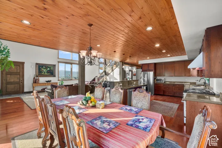 Open-concept living space featuring wood-finish flooring, a wood-paneled ceiling with recessed lighting, and a kitchen with wood cabinetry and stone countertops