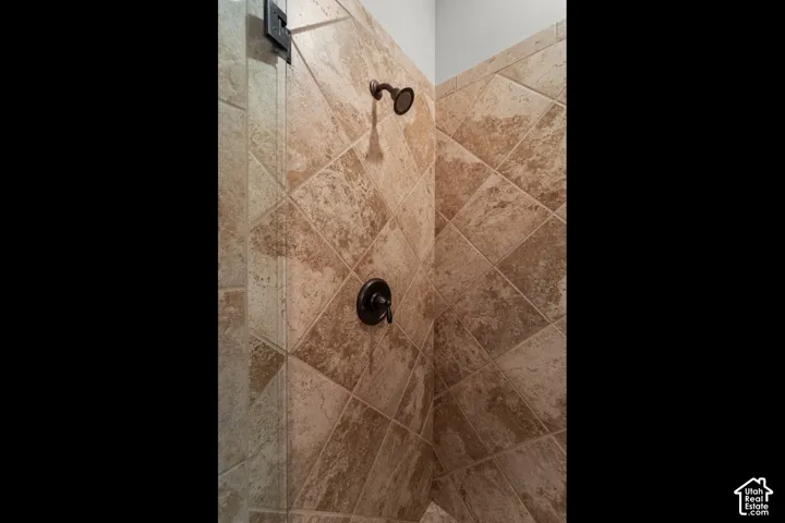 Tiled shower stall with diagonal tile pattern, bronze showerhead, and bronze control handle