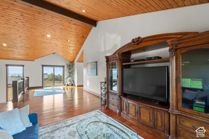 Vaulted wood-paneled ceiling with exposed beam, recessed lighting, polished wood-finish flooring, and sliding glass door to exterior