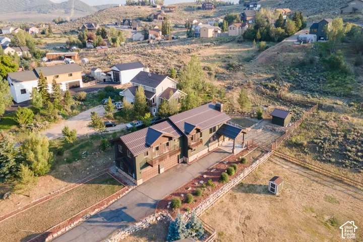 Property featuring a multi-level structure with a metal roof, an extended paved driveway, and a covered entry