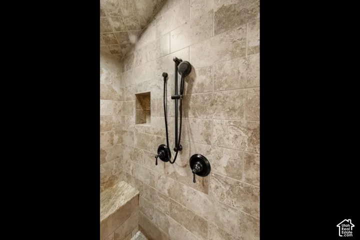 Tiled shower surround with a built-in bench, recessed niche, and dark bronze shower fixtures