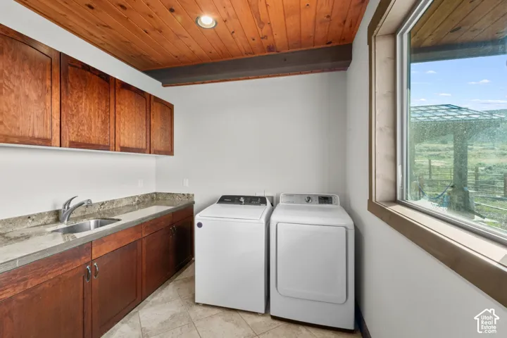 Wood-paneled ceiling with recessed lighting, wood-finish cabinetry, stone-finish countertop with an undermount sink, and tiled flooring