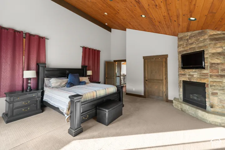 Vaulted wood-paneled ceiling with recessed lighting, floor-to-ceiling stone fireplace, and wood-paneled doors