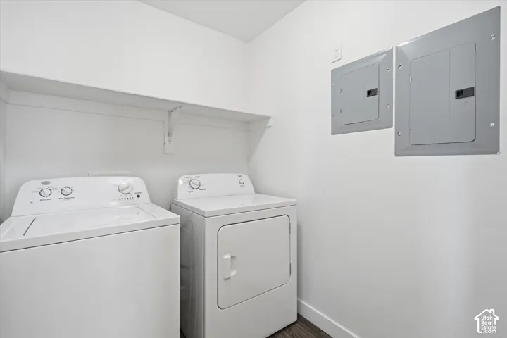 Laundry area featuring a built-in shelf, wood-finish flooring, and two electrical panels