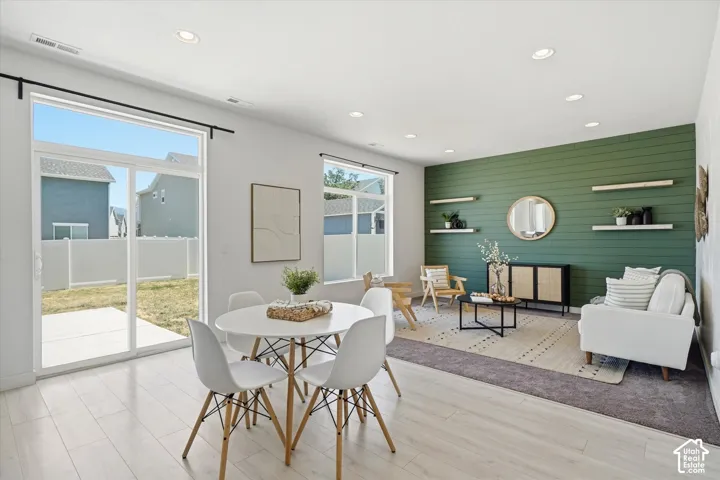 Recessed lighting, light wood-finish flooring, sliding glass patio door, accent wall with horizontal paneling, and floating shelves
