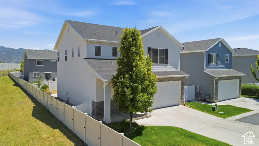 Modern two-story home with a two-car garage, stone veneer accents, and a privacy fence