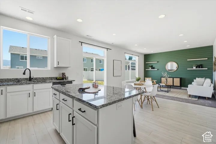 Kitchen island with gray granite countertop, white cabinetry, and matte black hardware