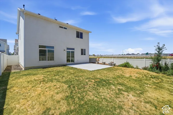 Rear exterior with a concrete patio, sliding glass door, and multiple windows