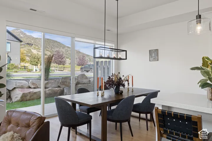 Expansive sliding glass doors, contemporary linear chandelier, light wood-finish flooring, white countertop, and recessed ceiling lighting