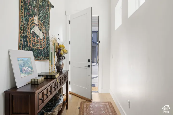 Entryway featuring a solid core door, light-toned wood-finish flooring, and white walls