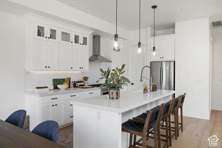 White cabinetry with glass-front uppers, stainless steel appliances, and a subway tile backsplash