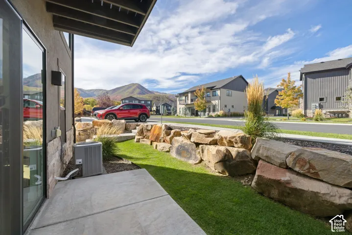 Outdoor patio with concrete pavers, stone veneer siding, and a landscaped rock retaining wall