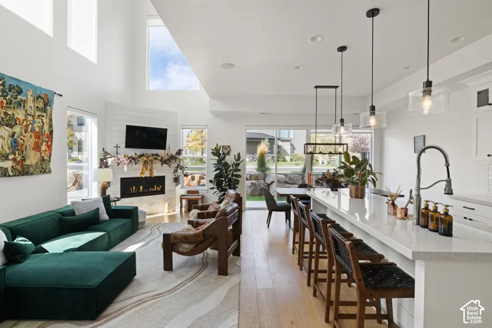 Open-concept living area with high ceilings, wood-finish flooring, and a fireplace with a textured surround