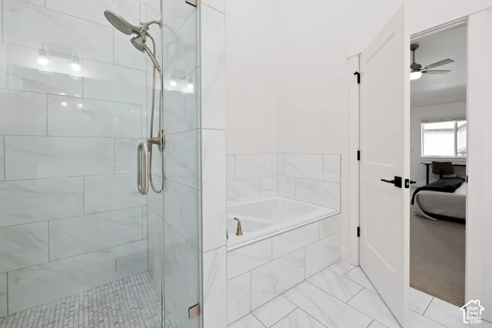 Glass-enclosed shower with brushed nickel fixtures, white tiled walls, and a tiled shower floor