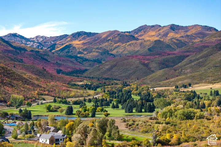Mountainous terrain with colorful foliage, expansive golf course, mature trees, and a pond feature