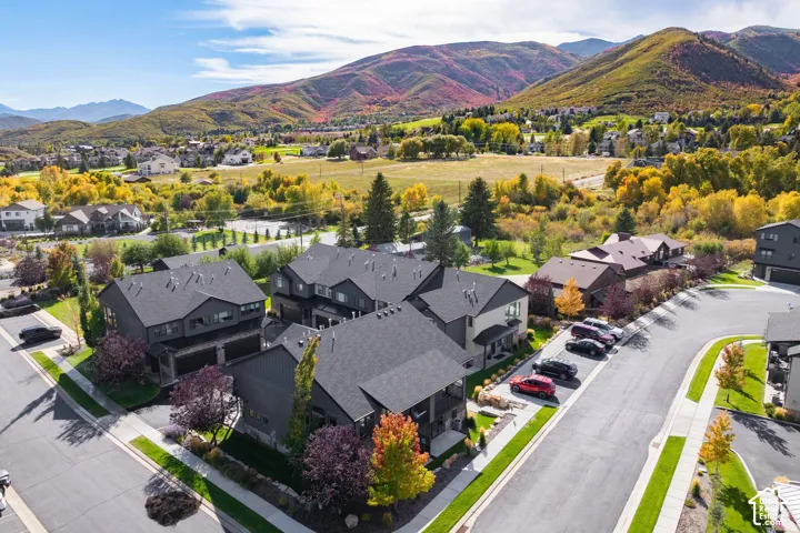 Modern residential architecture with dark-toned siding and pitched roofs, surrounded by landscaped grounds and paved streets