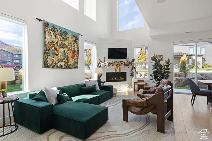 High vaulted ceilings, abundant natural light, a contemporary fireplace, wood-finish flooring, and expansive windows
