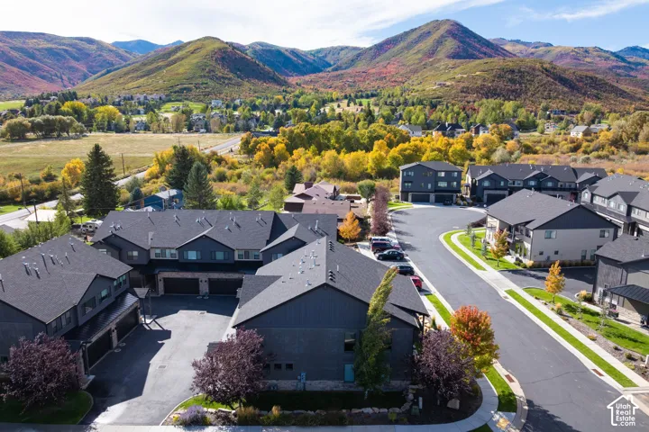 Modern multi-level residences with dark siding and shingle roofs, situated within a developed community featuring paved streets and established landscaping