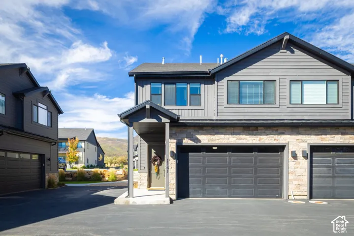 Contemporary exterior design featuring horizontal siding and stone accents, covered entry, and attached garages