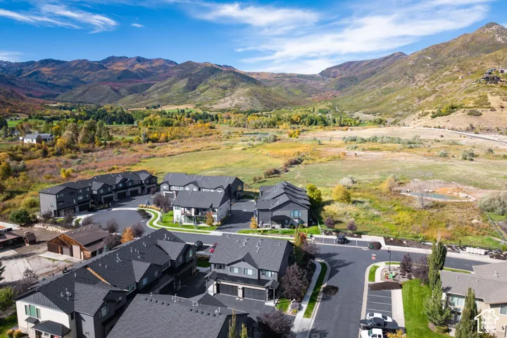 Modern townhome community with paved roadways and landscaping, set against a backdrop of mountainous terrain and varied natural foliage