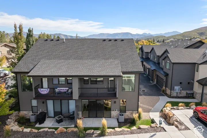 Contemporary exterior with a dark grey shingle roof, stucco siding, and stone accents