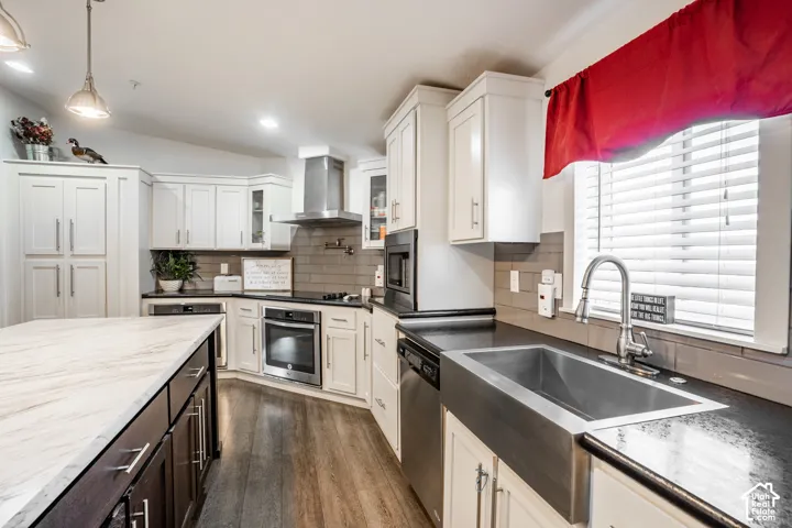 Chef's kitchen featuring white shaker cabinetry, stainless steel appliances including a professional-style range hood, and a large farmhouse sink with gooseneck faucet