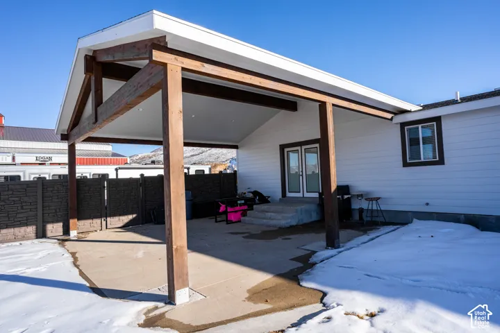 Expansive covered patio with exposed wood beams, concrete flooring, and direct access through double glass doors