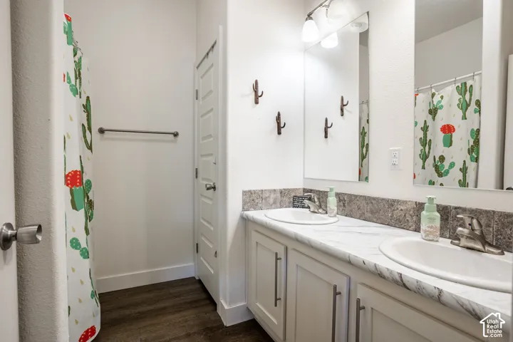 Spa-inspired bathroom featuring dual vanities with white cabinetry, marble countertops, and an integrated backsplash