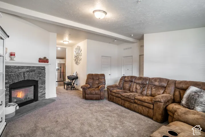 Spacious living room with wall-to-wall carpeting, gas fireplace with tile surround and mantel, recessed ceiling lighting, and multiple seating areas