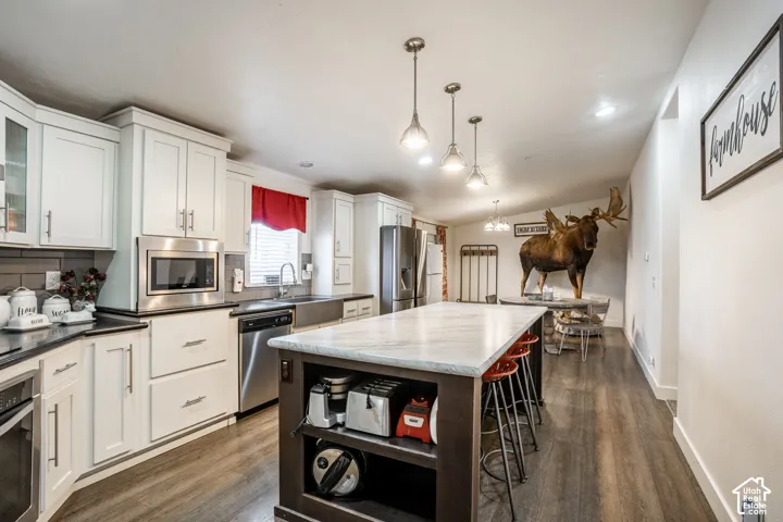 Chef's kitchen featuring white cabinetry with brushed nickel hardware, stainless steel appliances, and a large center island with black base and white quartz countertop