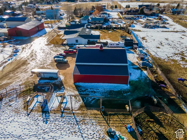 Additional contentThis aerial photograph shows an industrial or agricultural property with multiple large metal-roofed structures, equipment storage areas, and paved surfaces