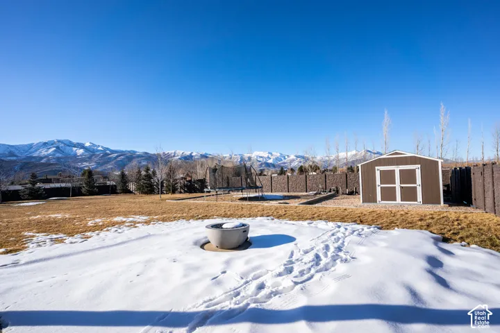 Expansive grounds featuring open acreage with seasonal snow cover, mature tree line, and outbuildings including a detached shed with white trim
