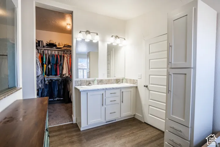 Primary bathroom featuring a white vanity with dual sinks, quartz countertop, polished chrome fixtures, and dual illuminated mirrors