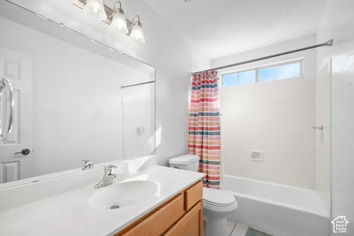 Bathroom featuring a wood-finish vanity with an integrated sink, a large wall-mounted mirror, brushed nickel faucet, and a shower/tub combination with a transom window