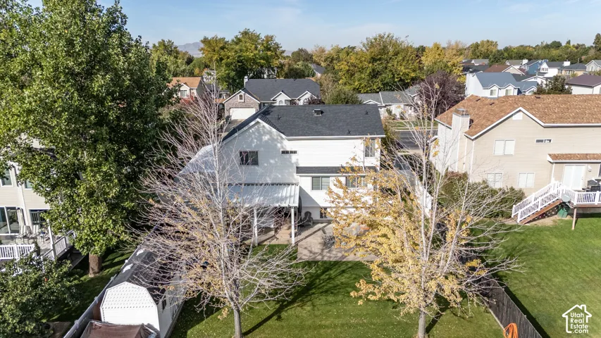 Expansive rear yard featuring a manicured lawn, established landscaping, and a patio with a covered pergola