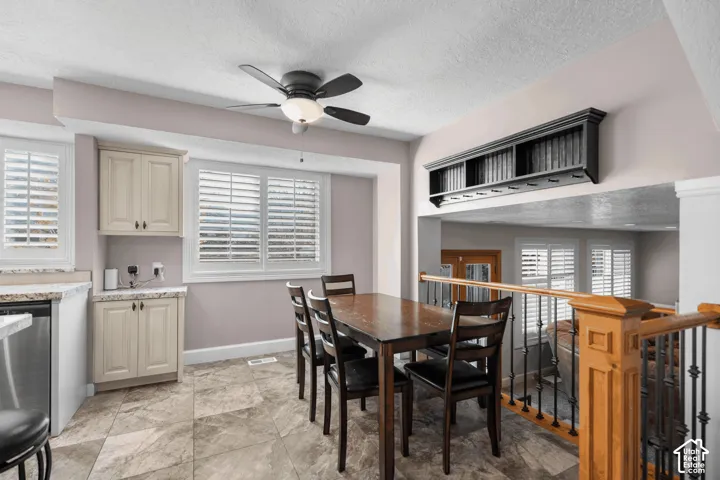 Kitchenette with cream cabinetry, light-toned countertops, and a stainless steel dishwasher