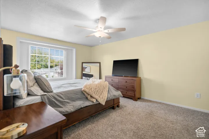 Window with white blinds, wood-finish flooring, ceiling fan, and light-toned walls