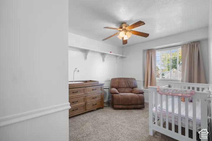Neutral wall paint, ceiling fan with integrated lighting, window with blinds, and wall shelving