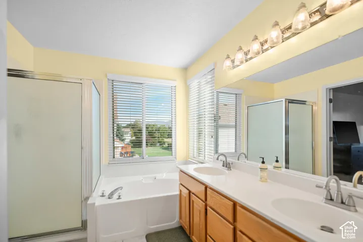 Dual vanity with wood-finish cabinetry, built-in bathtub, and a separate shower enclosure