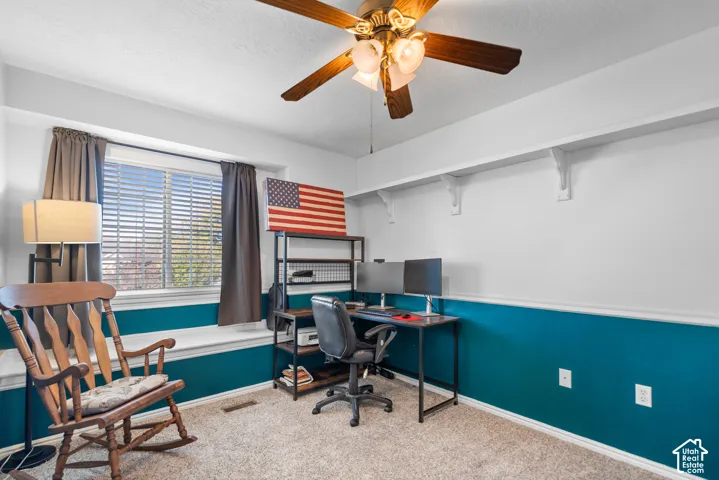 Carpeted room with a ceiling fan light fixture
