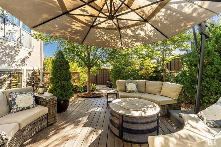 Wood-look composite deck with a built-in fire pit, surrounded by mature trees and privacy landscaping