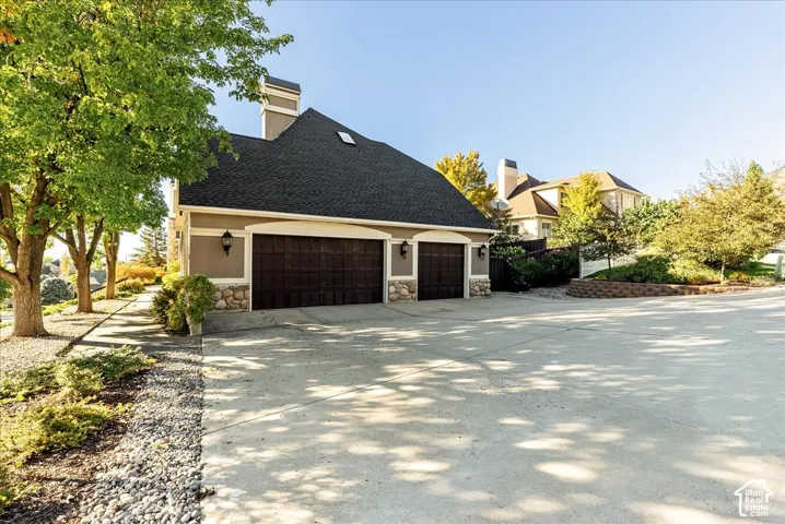 Two-car garage with wood-finish doors, exterior lighting fixtures, and stone detailing