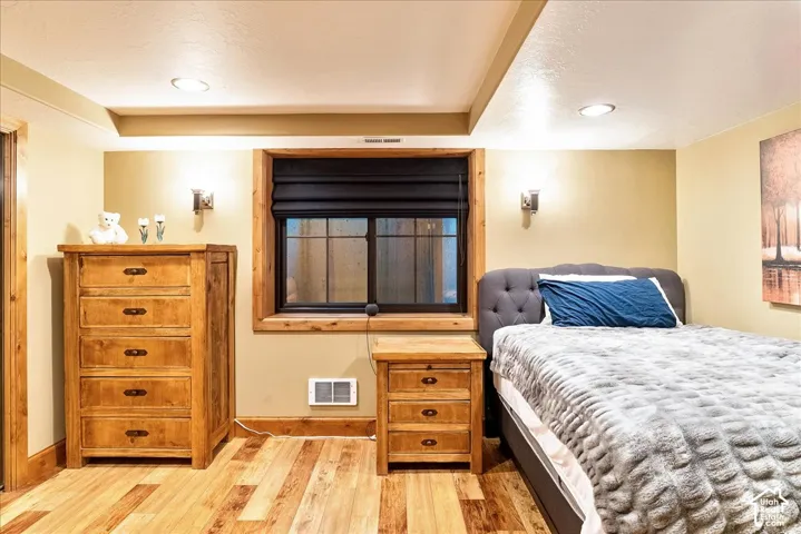 Recessed ceiling lighting, wood-finish flooring, wood trim window frame, and wall sconces