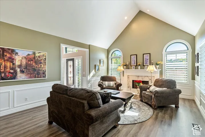 Vaulted ceilings, wood-finish flooring, white wainscoting, and a fireplace with a marble-style surround